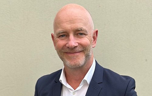 Gregor Zowierucha, CEO der PLATH GmbH & Co. KG, lächelt in die Kamera. Er trägt einen dunklen Anzug mit weißem Hemd. Der Hintergrund ist ein Büro.